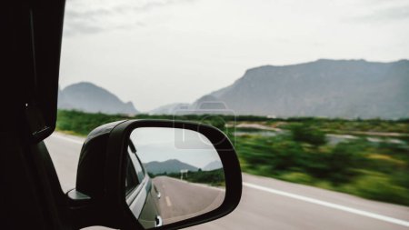 Photo for A close-up of a car rear view mirror while driving on an asphalt road or a freeway. - Royalty Free Image