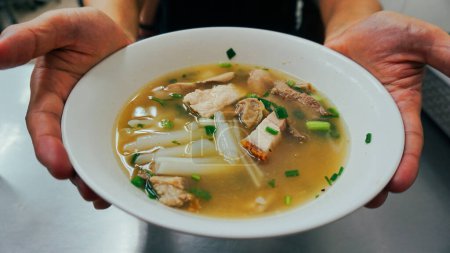 Tom Kuay Jap klare Suppe, Thai Street Food Menü. Paste aus Reismehl oder gekochter chinesischer Pasta mit knusprigem Schweinefleisch. Knusprige Schweinesuppe ist eine in erster Linie flüssige Speise, die in der Regel warm oder heiß serviert wird und durch die Kombination von Zutaten wie Fleisch und Gemüse hergestellt wird.