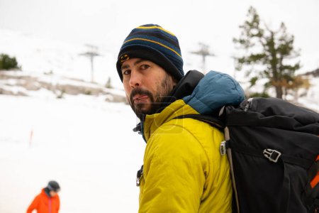 Téléchargez les photos : Photo de l'alpiniste avec chapeau, sac à dos et manteau montant la piste de ski. téléski en arrière-plan. et un autre homme - en image libre de droit