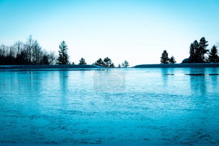 Foto de Lago de montaña congelado en invierno con árboles en el fondo del paisaje de invierno y gélido. copiar espacio en el cielo - Imagen libre de derechos