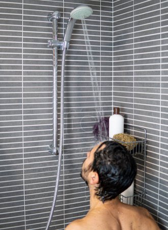 Experiencia de ducha contemporánea: baño de estilo urbano. hombre con pelo moreno bajo la ducha.