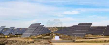 Expansive Solarfarm nutzt Sonnenlicht auf unwegsamem Gelände unter blauem Himmel.