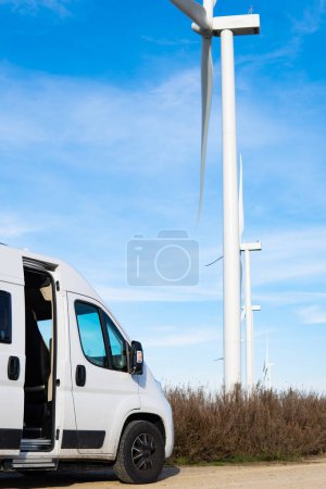 Efficient Mobile Workstation: White Van Parked by Wind Turbines in Field.