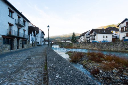 A small town with a river running through it. The houses are old and the street is cobblestone
