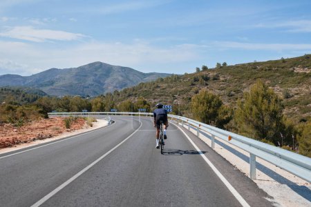 Photo for Cyclist training on road bike.Sport motivation.Cycling holiday in Spain.Man cyclist wearing cycling kit and helmet. Motivation image of an athlete. A male cyclist is cycling in the mountains - Royalty Free Image
