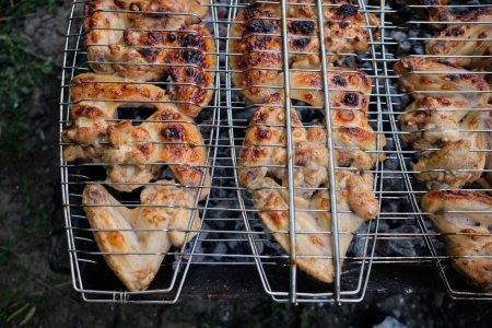 Photo for Barbecue grill chicken meat. Tasty chicken legs and wings on the grill with fire flames. - Royalty Free Image