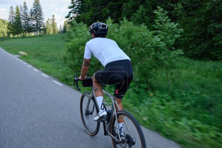 Foto de Hombre ciclista en una bicicleta de grava está montando en la carretera en las colinas con una vista de las montañas.Entrenamiento ciclista en bicicleta de carretera en la montaña. Motivación deportiva. - Imagen libre de derechos