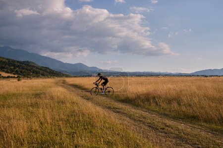 Photo for Male cyclist wearing cycling kit and helmet riding on the road a gravel bike at sunset.Sports motivation image. - Royalty Free Image
