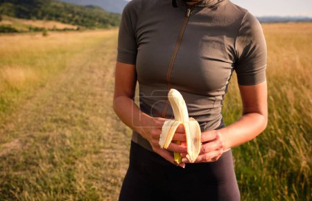 Foto de Ciclista sosteniendo un plátano. Nutrición saludable de un ciclista. Snack saludable para un ciclista durante el entrenamiento. - Imagen libre de derechos