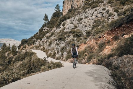 Photo for Man cyclist  wearing cycling kit and helmet.Man riding on bicycle in the mountains.Male cyclist is riding on bicycle in the mountains.Serra de Bernia,Alicante, Spain - Royalty Free Image