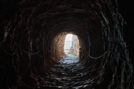 Foto de Túnel de roca en las montañas - Parque Natural de Penyal d 'Ifac. Cuerdas en las paredes.Calpe, Alicante, España. - Imagen libre de derechos