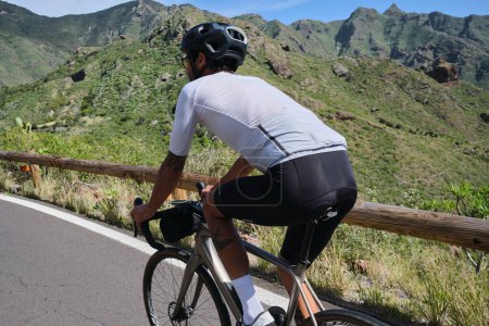 Foto de Hombre ciclista montando bicicleta de grava con bolsa de manillar en la carretera en Anaga Park, Tenerife. Imagen de motivación deportiva.Ciclismo en hermosa naturaleza.Hombre ciclista con kit de ciclismo y casco - Imagen libre de derechos