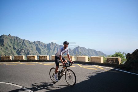 Foto de Hombre ciclista montando bicicleta de grava con bolsa de manillar en la carretera en Anaga Park, Tenerife. Imagen de motivación deportiva.Ciclismo en hermosa naturaleza.Hombre ciclista con kit de ciclismo y casco - Imagen libre de derechos