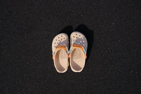 Photo for Top view of flip flops on beach. Detailed black sand texture. Sandy beach background. Top view and copy space. Yellow slippers on black sand at the beach. Tenerife Island.Holiday vacations concept. - Royalty Free Image
