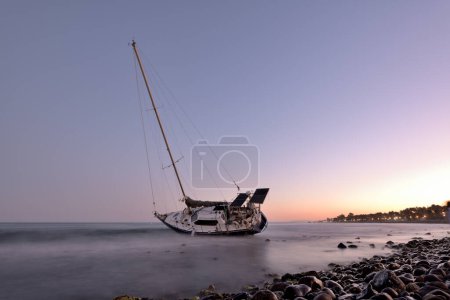 Photo for Sailboat aground on a beach in Marbella at sunset - Royalty Free Image