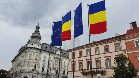 Téléchargez les photos : Drapeaux roumains et européens flottant sur Piata Unirii (Place de l'Union) à Cluj-Napoca, Roumanie. Septembre 2023. - en image libre de droit