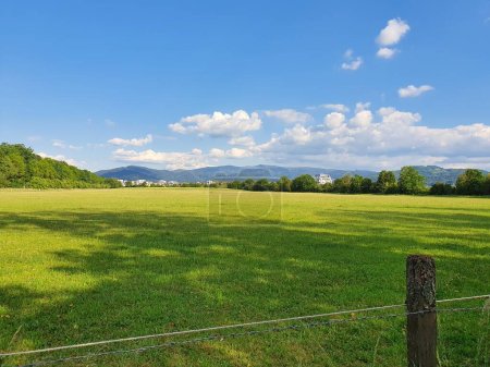 Soleil sur un terrain vert clair à Fribourg, Allemagne (mai 2020). Nuages moelleux et montagnes visibles au loin. 