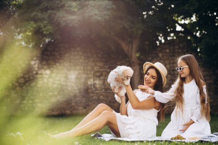 Téléchargez les photos : Mère avec fille et animal de compagnie dans la cour arrière ayant pique-nique avec des beignets - en image libre de droit