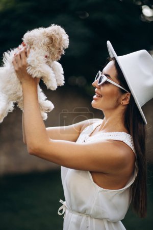 Téléchargez les photos : Belle femme tenant son petit chien maltipa - en image libre de droit