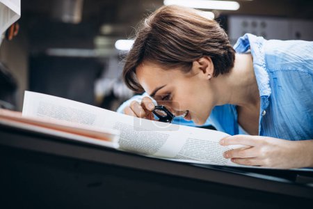 Téléchargez les photos : Femme travaillant dans une imprimerie avec papier et loupe - en image libre de droit