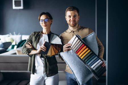 Mujer y hombre diseñador con muestras textiles y paleta de madera en la tienda de muebles