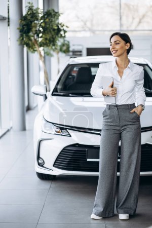 Photo for Young saleswoman with tablet in a car showroom - Royalty Free Image