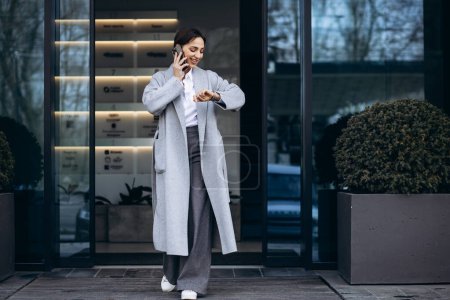 Photo for Business woman talking on the phone outside office bulding - Royalty Free Image