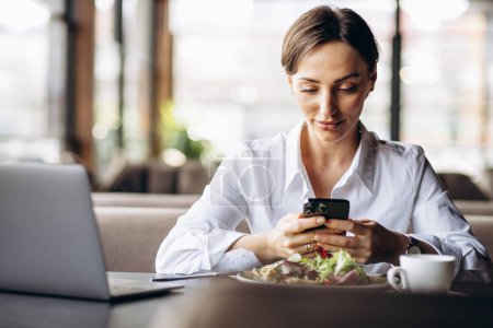 Téléchargez les photos : Femme d'affaires travaillant sur ordinateur portable et manger de la salade - en image libre de droit