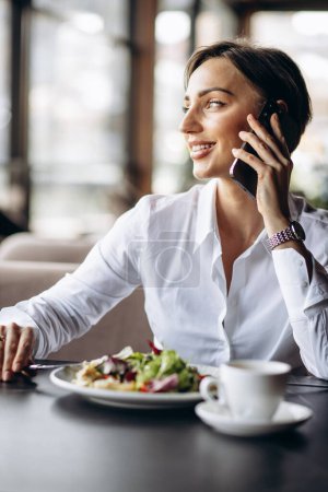 Téléchargez les photos : Femme d'affaires travaillant sur ordinateur portable et manger de la salade - en image libre de droit
