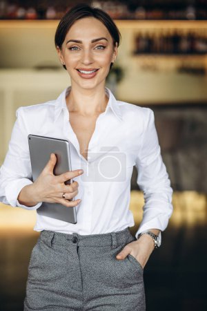 Téléchargez les photos : Femme d'affaires tenant la tablette dans un café - en image libre de droit