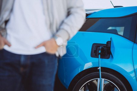 Photo for Man charging blue electric car - Royalty Free Image