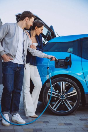 Photo for Couple charging their new electric car - Royalty Free Image