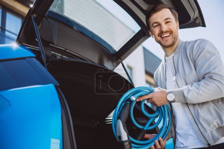 Photo for Man holding charger from electric car - Royalty Free Image