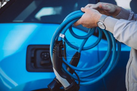 Photo for Man holding charger from electric car - Royalty Free Image