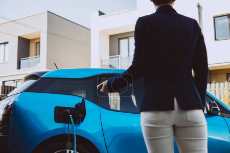 Téléchargez les photos : Femme fermant sa voiture électrique charge - en image libre de droit