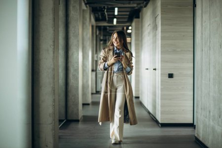 Foto de Mujer de negocios usando el teléfono y caminando en la oficina - Imagen libre de derechos