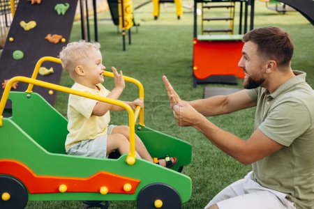 Téléchargez les photos : Père avec fils sur l'aire de jeux s'amuser - en image libre de droit