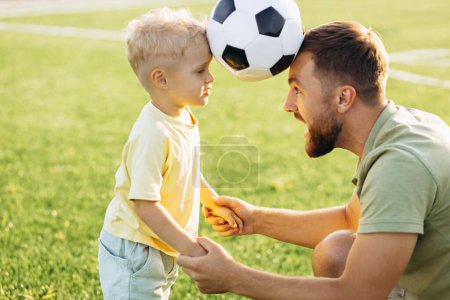 Téléchargez les photos : Père avec son fils jouant au football sur le terrain de football - en image libre de droit