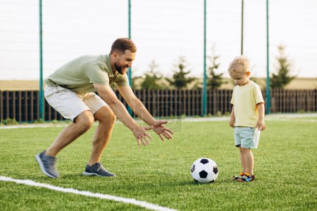 Foto de Padre con hijo jugando fútbol en el campo de fútbol - Imagen libre de derechos