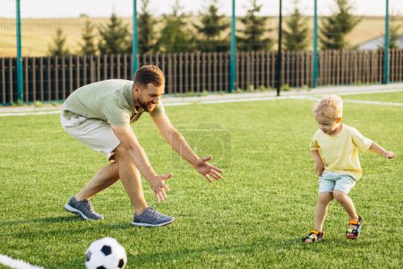 Téléchargez les photos : Père avec son fils jouant au football sur le terrain de football - en image libre de droit