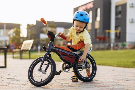 Téléchargez les photos : Petit garçon mignon apprenant à faire du vélo - en image libre de droit