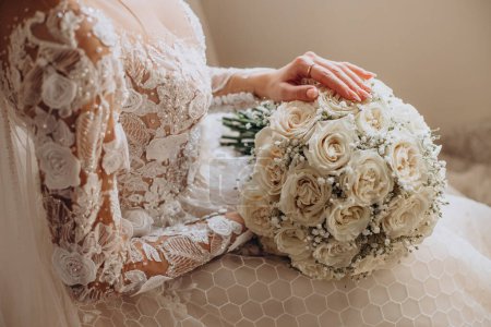Téléchargez les photos : Mariée assise sur une chaise tenant son bouquet de mariage - en image libre de droit
