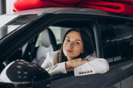 Photo for Woman sitting in her new car in a car showroom - Royalty Free Image
