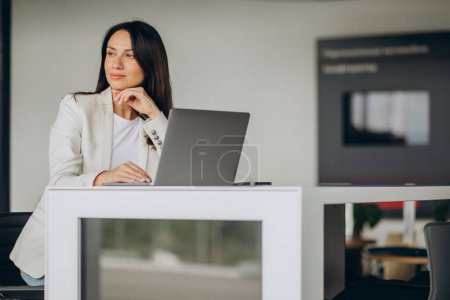 Photo for Business woman working on a laptop at the office of car showroom - Royalty Free Image