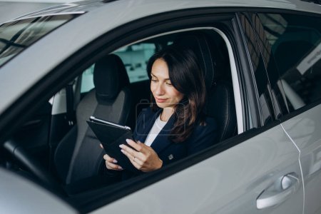 Photo for Business woman sitting in her new car with tablet - Royalty Free Image