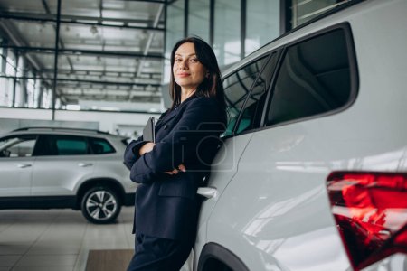 Photo for Sales woman in car showroom standing by a car - Royalty Free Image