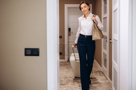 Photo for Business woman walking into hotel room with luggage - Royalty Free Image