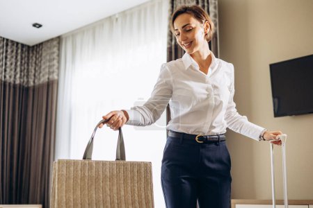 Téléchargez les photos : Femme d'affaires entrant dans la chambre d'hôtel avec des bagages - en image libre de droit