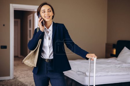 Foto de Mujer de negocios en una habitación de hotel hablando por teléfono y llevando equipaje - Imagen libre de derechos