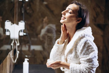 Téléchargez les photos : Femme appliquant crème hydratante pour le visage - en image libre de droit